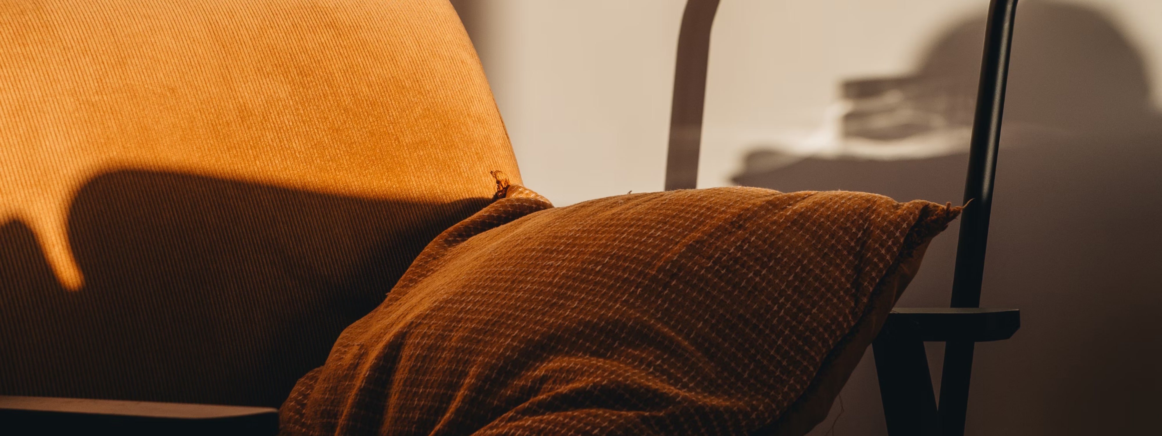 Warm-toned textured cushions draped over a chair with soft shadows