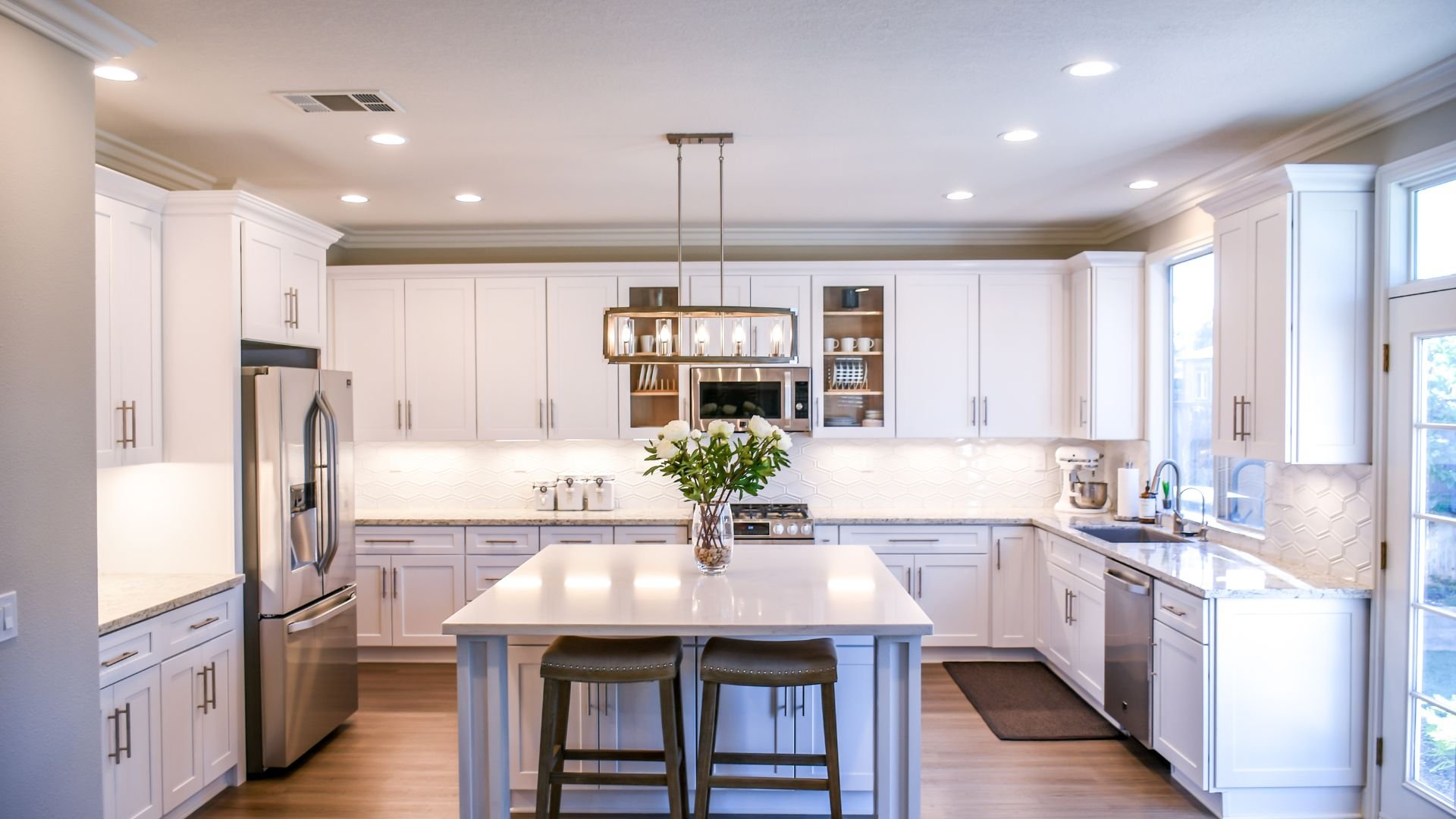 Modern white kitchen with island, bar stools, and pendant lighting
