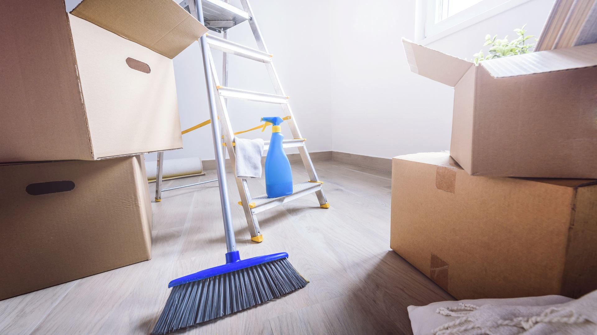 Moving day with cardboard boxes, ladder, broom, and cleaning spray