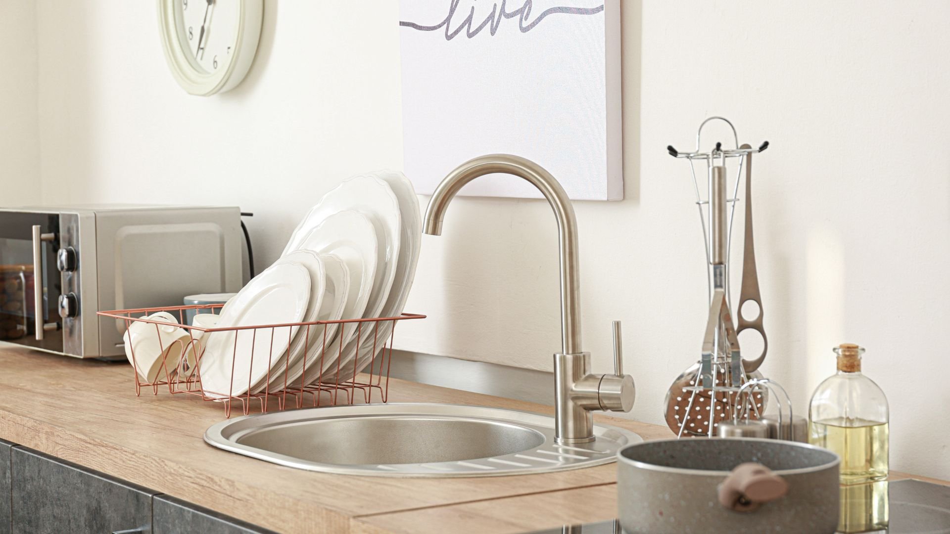 Modern kitchen sink with dishes, faucet, and copper dish rack