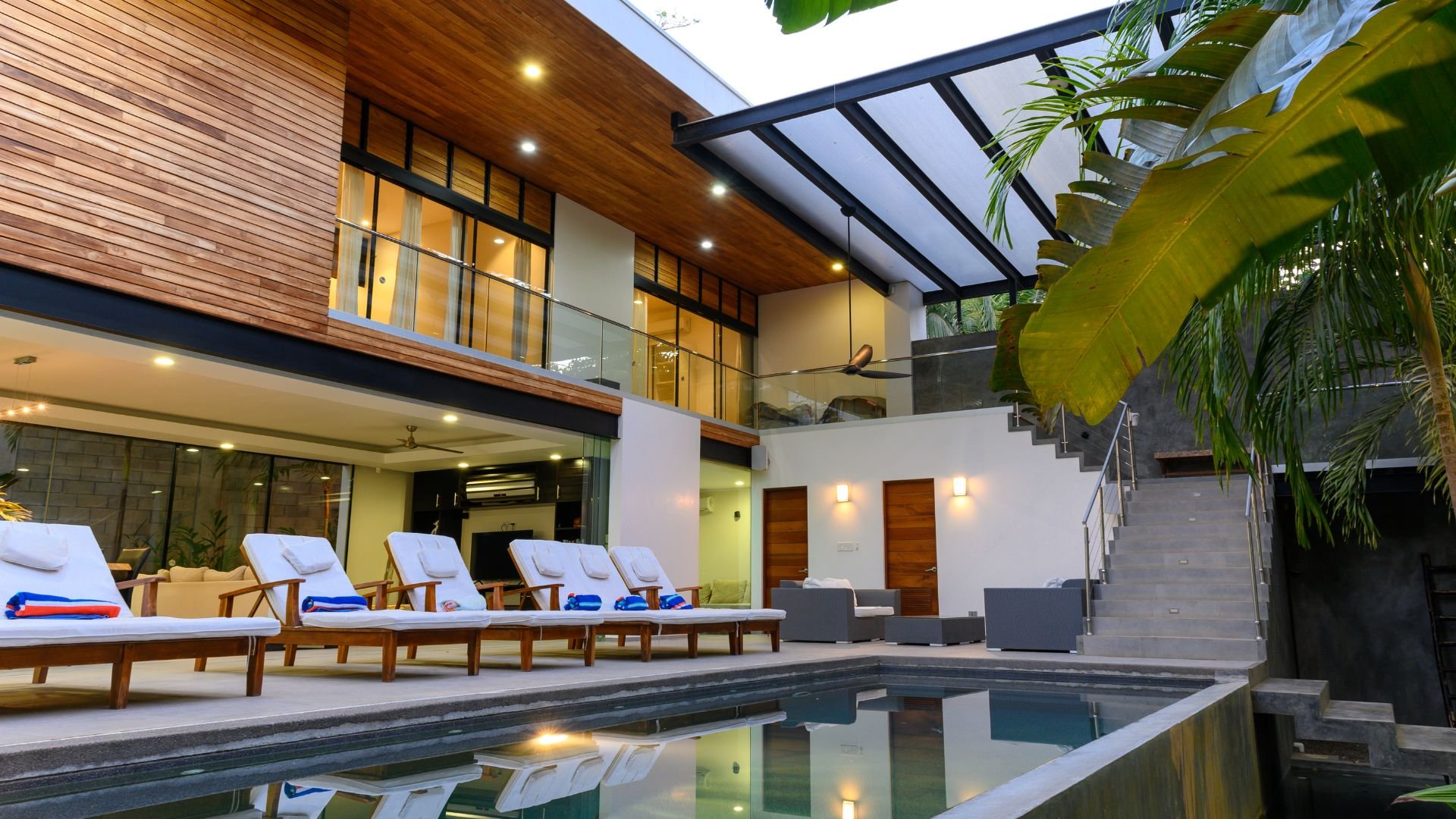 Modern tropical villa with pool, lounge chairs, and lush green plants